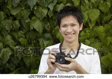 Picture - Portrait of a young man holding camera. Fotosearch