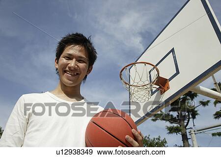 Stock Photo - Portrait of a young man holding basketball. Fotosearch