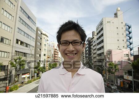 Stock Photography - Portrait of a young man smiling with buildings in background. Fotosearch