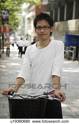 Stock Image - Portrait of a young man with bicycle. Fotosearch