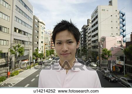 Stock Image - Portrait of a young man with buildings in background. Fotosearch