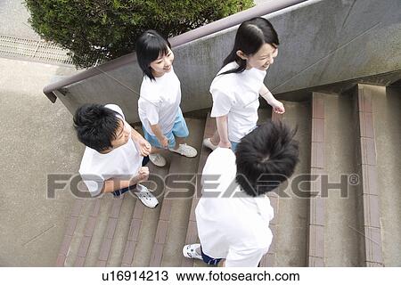Stock Image - Four teenagers in gym clothes smiling and walking up the stairs. Fotosearch