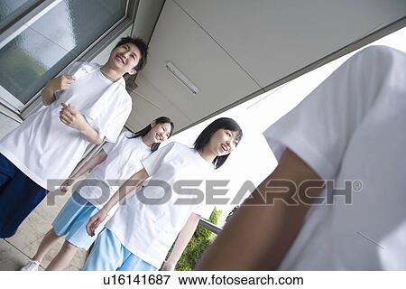 Stock Photo - Four teenagers in gym clothes walking at outside corridor. Fotosearch