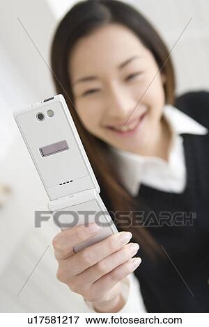 Stock Photo - Girl holding and looking at mobile phone, front view. Fotosearch