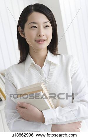 Girl holding textbooks, smiling, front view View Large Photo Image Stock Photograph - Girl holding textbooks, smiling, front view. Fotosearch