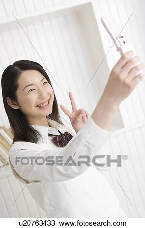 Girl taking a picture with mobile phone, smiling, front view View Large Photo Image Stock Image - Girl taking a picture with mobile phone, smiling, front view. Fotosearch