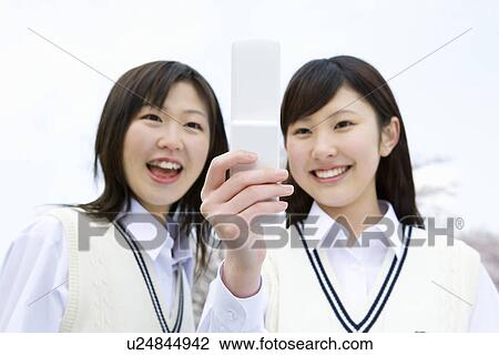 Stock Image - High School Girls Smiling and Looking at Mobile Phone. Fotosearch