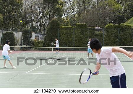 Stock Image - High School Students Playing Tennis on Ground. Fotosearch