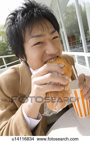 Teenage boy eating bread and holding disposable cup at terrace View Large Photo Image Picture - Teenage boy eating bread and holding disposable cup at terrace. Fotosearch