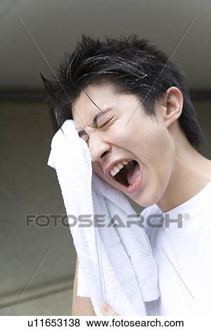 Stock Photo - Teenage boy in gym cloth drying face with towel and yelling. Fotosearch