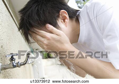Stock Image - Teenage boy in gym cloth washing face, blurred motion. Fotosearch