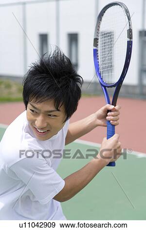 Stock Photo - Teenage boy smiling and holding tennis racket. Fotosearch
