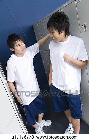Stock Image - Teenage boys in gym clothes smiling and standing in locker room. Fotosearch