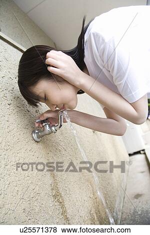 Stock Photo - Teenage girl in gym cloth drinking water from tap. Fotosearch