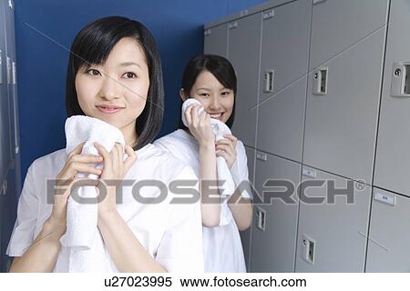 Stock Photography - Teenage girls in gym clothes wiping face with towels in locker room, smiling. Fotosearch