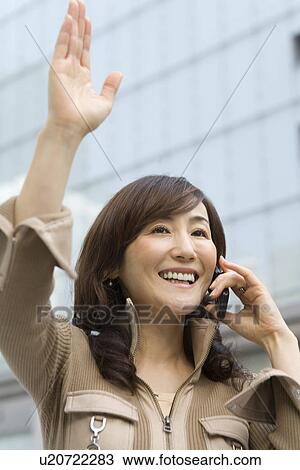 A Mature Adult Woman Talking on a Mobile Phone and Waving Her Hand, Low Angle View, Differential Focus View Large Photo Image Stock Image - A Mature Adult Woman Talking on a Mobile Phone and Waving Her Hand, Low Angle View, Differential Focus. Fotosearch