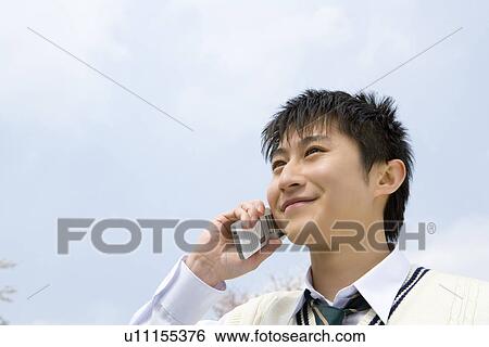 Stock Photograph - High School Boy Talking on Mobile Phone Under the Sky. Fotosearch