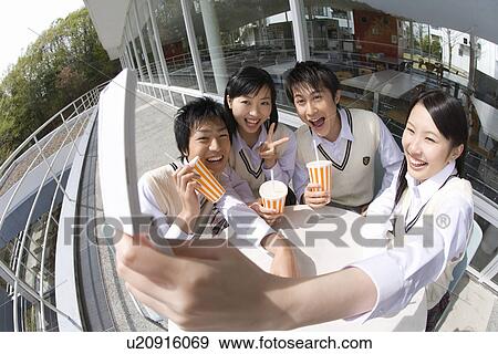 Stock Photo - High school students smiling and photographing with mobile phone, fish-eye lens. Fotosearch