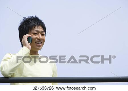 Man using mobile phone under the blue sky, front view, blue background, copy space, Japan View Large Photo Image Stock Photograph - Man using mobile phone under the blue sky, front view, blue background, copy space, Japan. Fotosearch