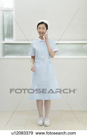 Stock Photo - Portrait of a nurse using mobile phone, smiling, front view. Fotosearch