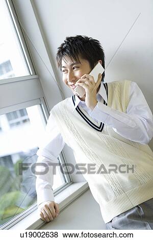 Teenage boy using mobile phone beside the window, smiling View Large Photo Image Stock Photo - Teenage boy using mobile phone beside the window, smiling. Fotosearch