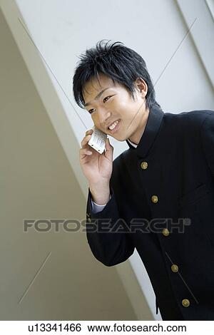 Stock Photograph - Teenage boy using mobile phone in classroom, smiling. Fotosearch