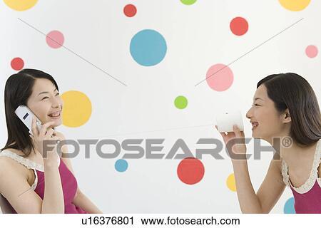 Two Young Twin Sisters Using a Mobile Phone and String Telephone, Side View View Large Photo Image Stock Image - Two Young Twin Sisters Using a Mobile Phone and String Telephone, Side View. Fotosearch