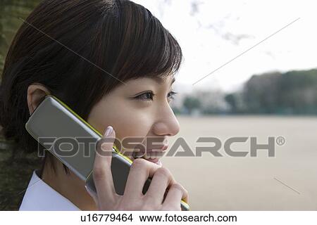 Picture - Woman using a mobile phone, side view, close up, Japan. Fotosearch