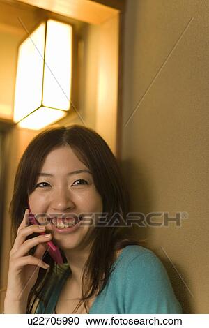 Stock Image - Woman using mobile phone in Japanese inn, front view, Japan. Fotosearch