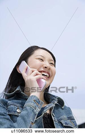 Woman using mobile phone under the blue sky, low angle view, blue background, Japan View Large Photo Image Stock Image - Woman using mobile phone under the blue sky, low angle view, blue background, Japan. Fotosearch
