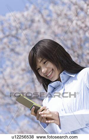 Young Woman Looking at a Mobile Phone, Low Angle View View Large Photo Image Stock Photo - Young Woman Looking at a Mobile Phone, Low Angle View . Fotosearch