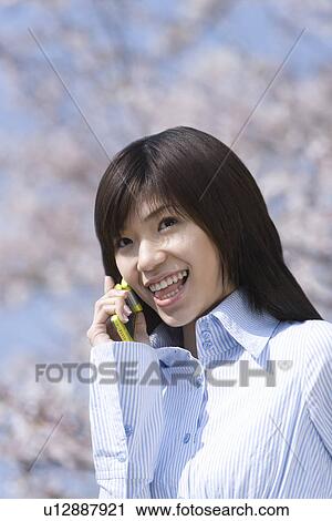 Stock Image - Young Woman Talking on Mobile Phone, Differential Focus, Side View . Fotosearch
