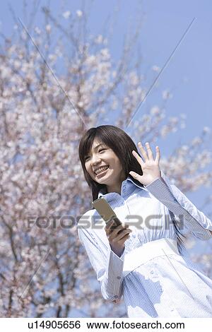 Stock Photograph - Young Woman Weaving her Hand Under Cherry Tree, Low Angle View. Fotosearch