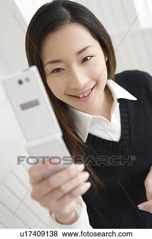 Girl holding and looking at mobile phone, front view View Large Photo Image Stock Photo - Girl holding and looking at mobile phone, front view. Fotosearch