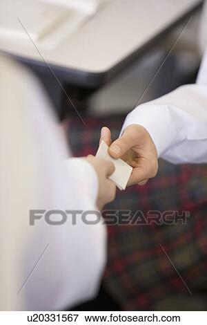 Stock Photo - High school students exchanging memo during class. Fotosearch
