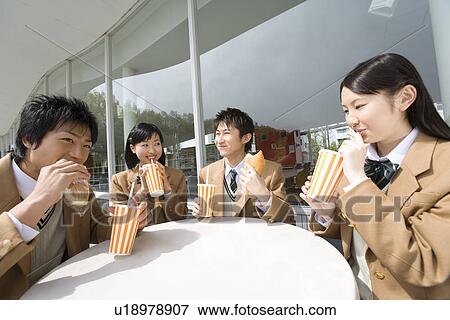 Stock Photo - High school students having lunch at terrace, smiling. Fotosearch