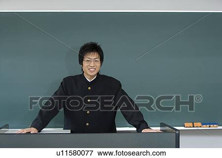Stock Photo - Portrait of a teenage boy standing in front of blackboard, smiling and looking at camera. Fotosearch