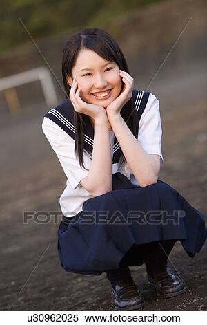 Portrait of a teenage girl sitting and resting chin in hands in schoolyard, smiling and looking at camera View Large Photo Image Stock Photography - Portrait of a teenage girl sitting and resting chin in hands in schoolyard, smiling and looking at camera. Fotosearch