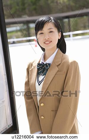 Picture - Portrait of a teenage girl standing at bus stop, looking at camera. Fotosearch
