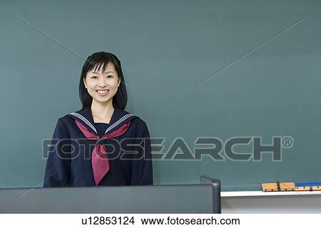 Portrait of a teenage girl standing in front of blackboard, smiling and looking at camera, green background View Large Photo Image Picture - Portrait of a teenage girl standing in front of blackboard, smiling and looking at camera, green background. Fotosearch