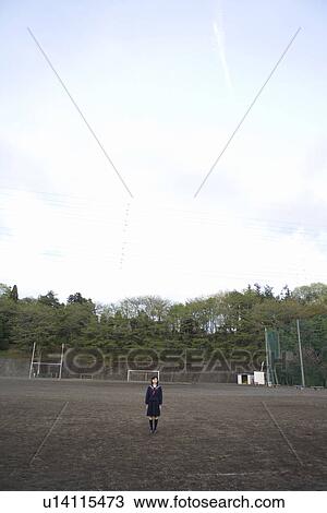 Stock Image - Portrait of a teenage girl standing in schoolyard, copy space. Fotosearch