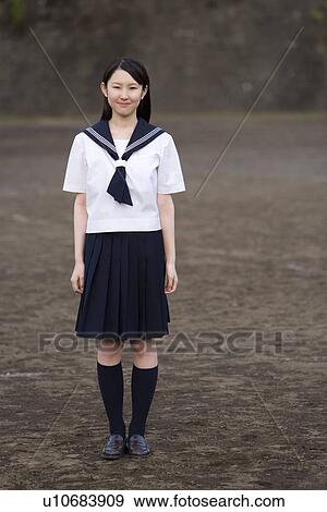 Stock Photo - Portrait of a teenage girl standing in schoolyard, smiling and looking at camera. Fotosearch