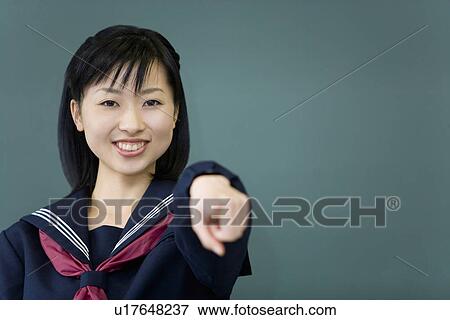 Portrait of a teenage girl standing in front of blackboard and pointing forward, looking at camera, green background View Large Photo Image Stock Photo - Portrait of a teenage girl standing in front of blackboard and pointing forward, looking at camera, green background. Fotosearch