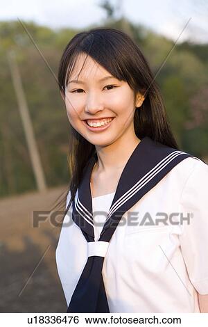 Stock Photograph - Portrait of a teenage girl standing in schoolyard, smiling and looking at camera. Fotosearch