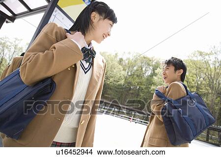 Teenage boy and girl smiling to each other at bus stop View Large Photo Image Picture - Teenage boy and girl smiling to each other at bus stop. Fotosearch