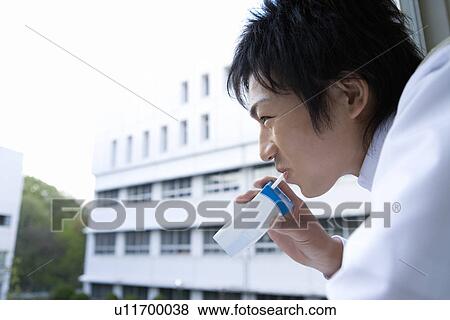 Stock Photo - Teenage boy smiling and drinking juice at window. Fotosearch