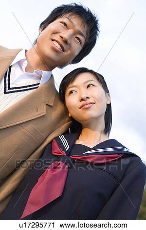 Teenage couple standing in schoolyard, girl leaning head on boy View Large Photo Image Stock Image - Teenage couple standing in schoolyard, girl leaning head on boy. Fotosearch