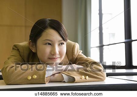 Teenage girl sitting and leaning on desk in classroom, smiling View Large Photo Image Stock Photography - Teenage girl sitting and leaning on desk in classroom, smiling. Fotosearch