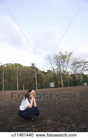 Teenage girl sitting and resting chin in hands in schoolyard, smiling View Large Photo Image Stock Image - Teenage girl sitting and resting chin in hands in schoolyard, smiling. Fotosearch