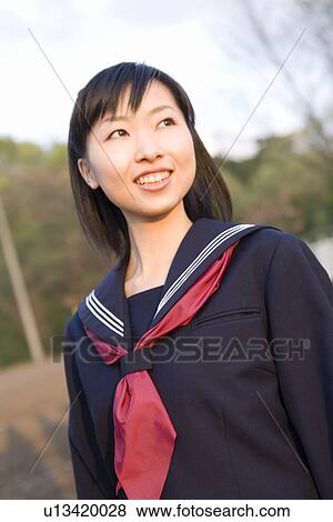Stock Photo - Teenage girl smiling and standing in schoolyard, looking away. Fotosearch